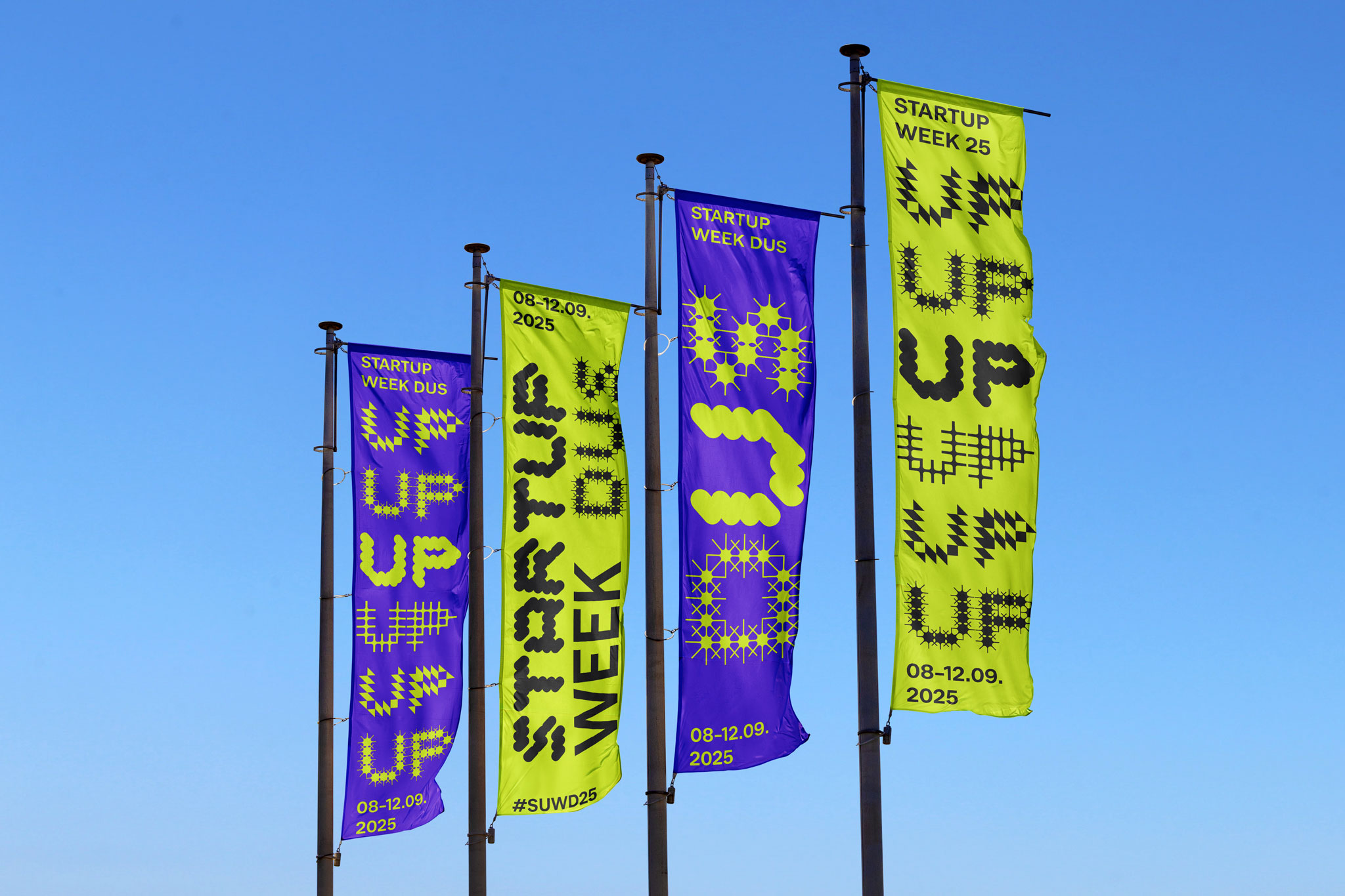 Bunte Fahnen der Startup Week Düsseldorf 2025 mit dem Motto "UP UP UP" und leuchtendem Grafikdesign in Blau und Gelb.